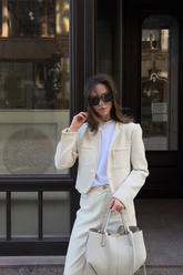 a lady in a white collarless jacket and a pair of white pants